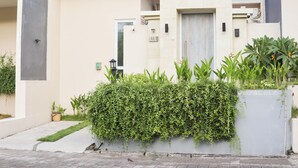 A modern building with a flat facade, a door, and a small window. There is a hedge in front of the building. - Otia Villa by Premier Hospitality Asia (Nusa Dua)