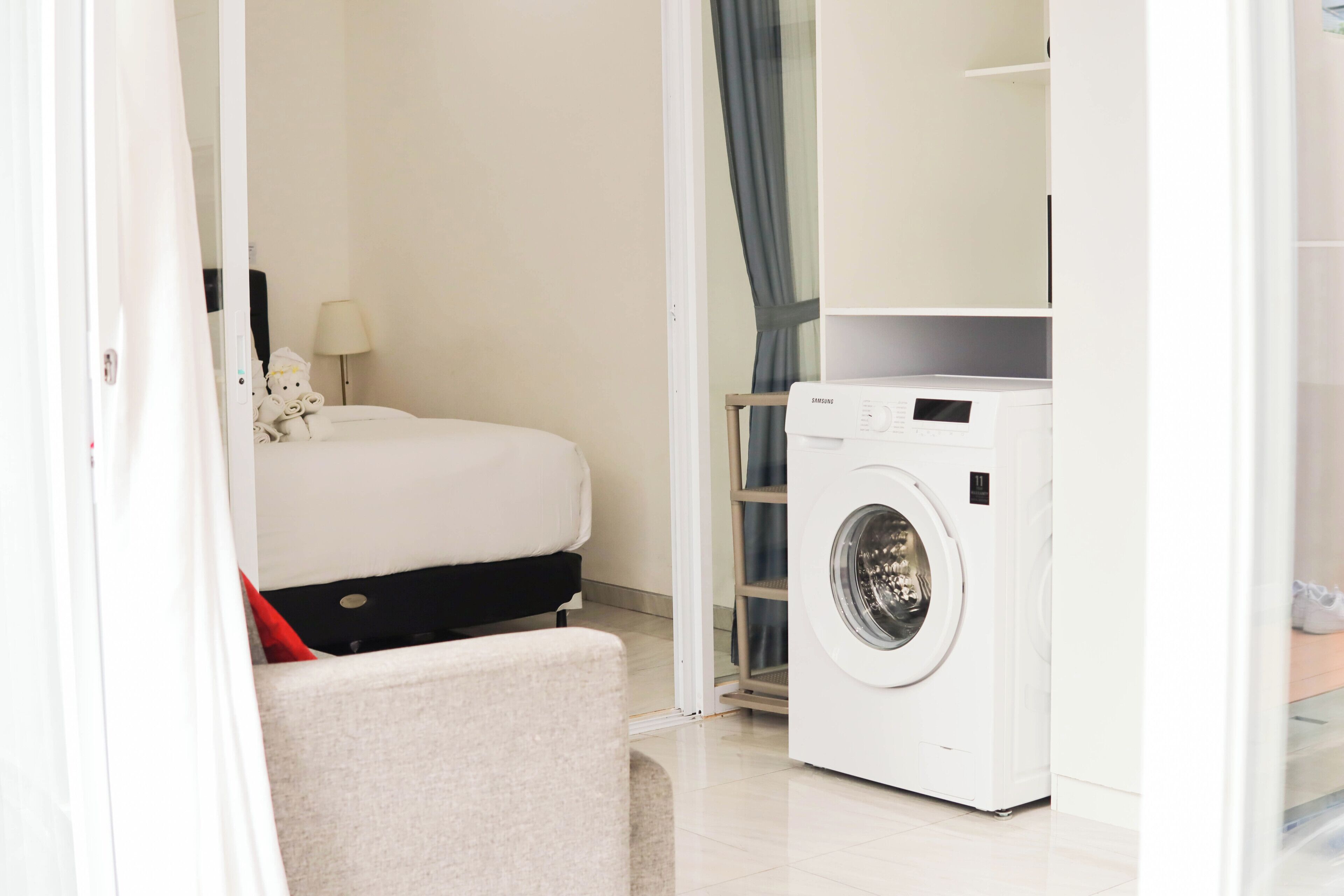A hotel room with a bed, a washing machine, and a small seating area.