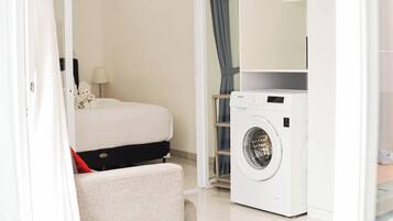 A hotel room with a bed, a washing machine, and a small seating area.