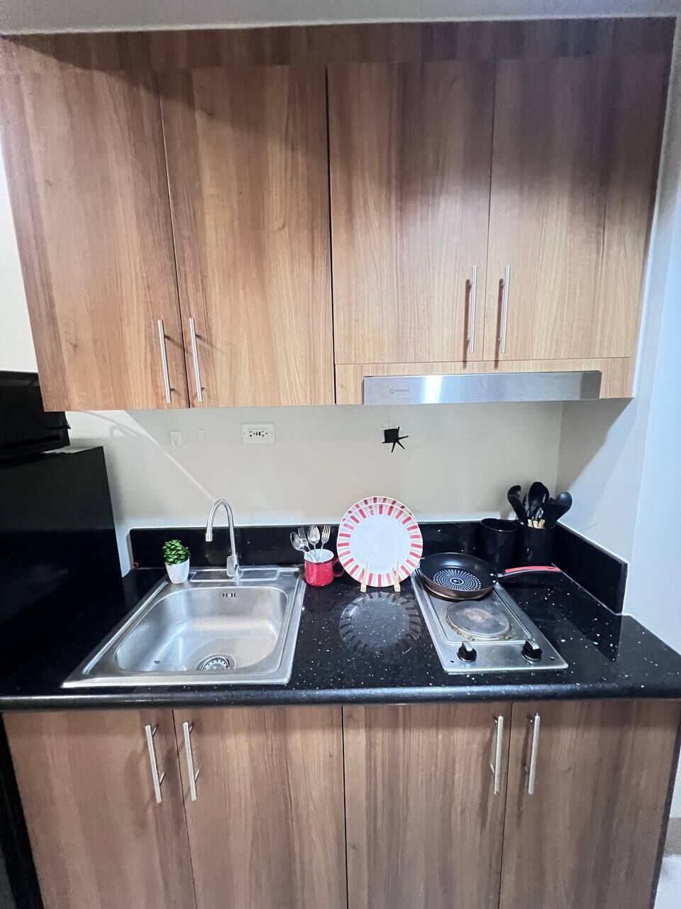 A kitchen with wooden cabinets, a stainless steel sink, a gas stove, and a small potted plant.