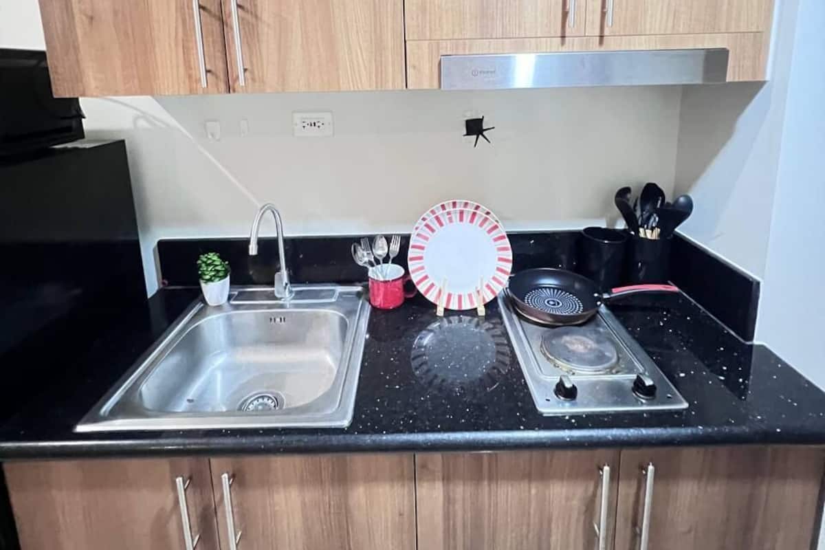 A kitchen with wooden cabinets, a stainless steel sink, a gas stove, and a small potted plant.