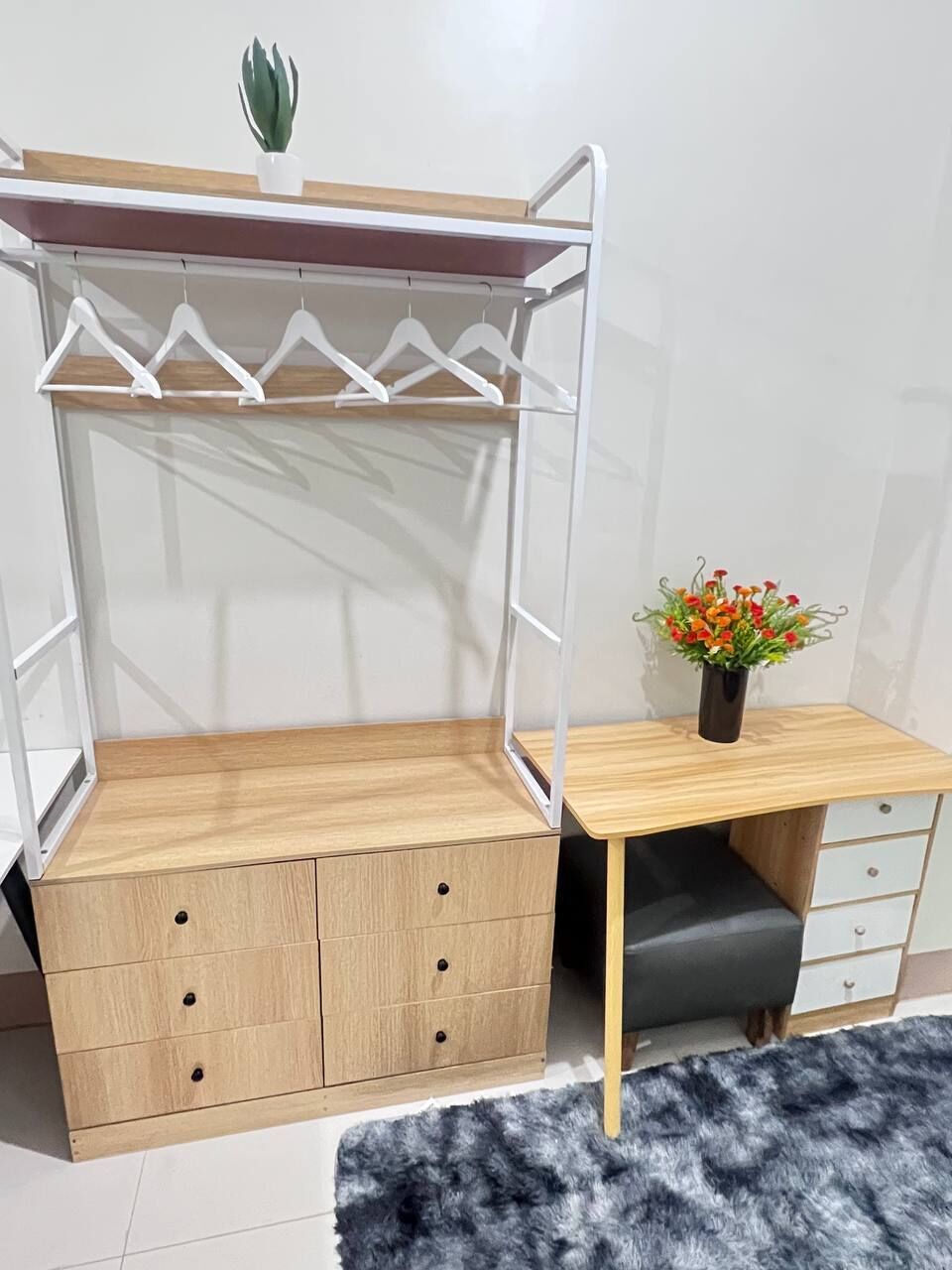 Un lit superposé avec un bureau et des tiroirs, une petite plante en pot et un tapis moelleux.