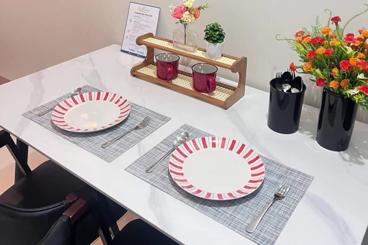 A dining table with two plates, a menu, a vase with flowers, and a small plant.