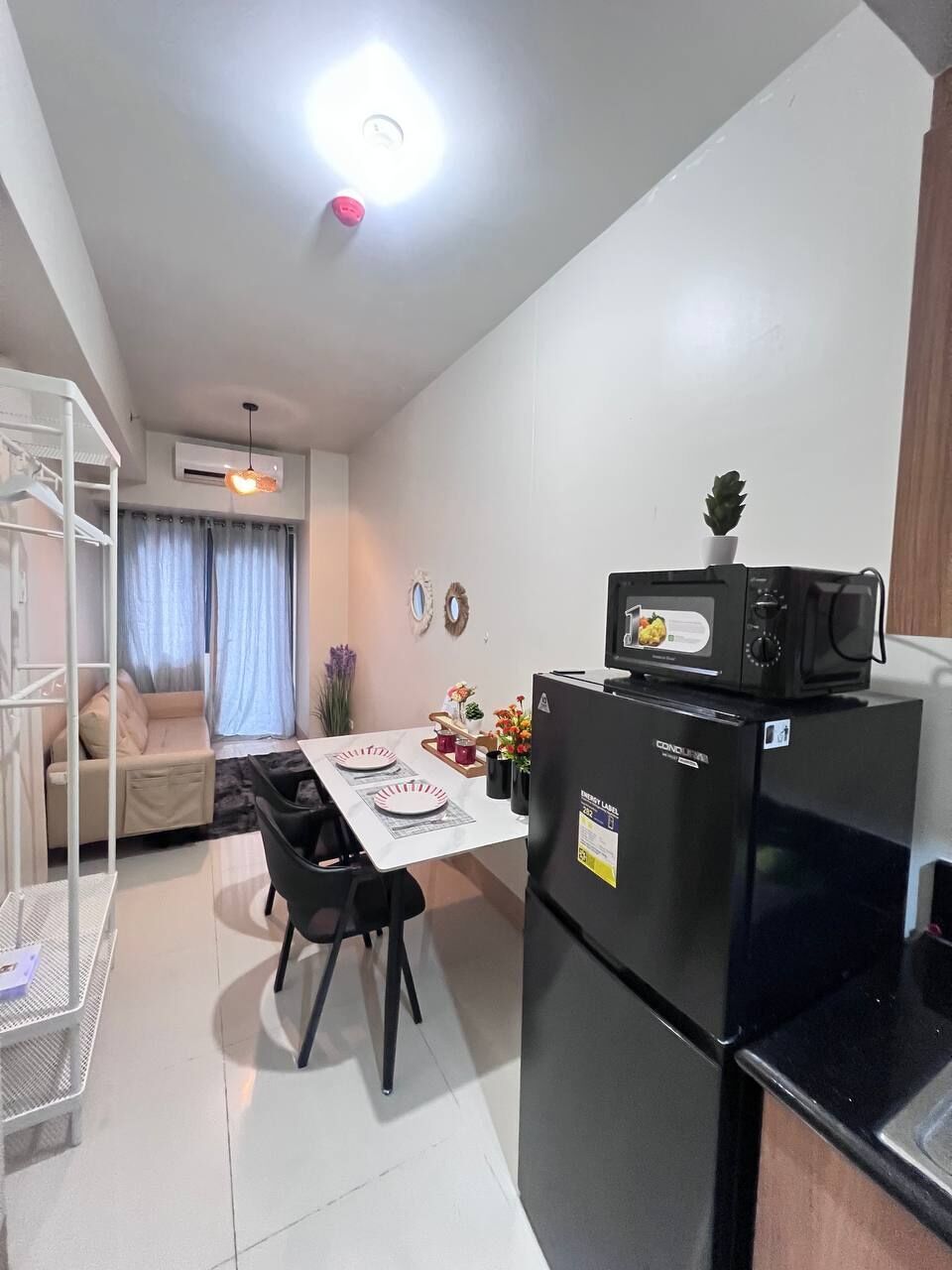 Cocina compacta con refrigerador, microondas y mesa para dos.