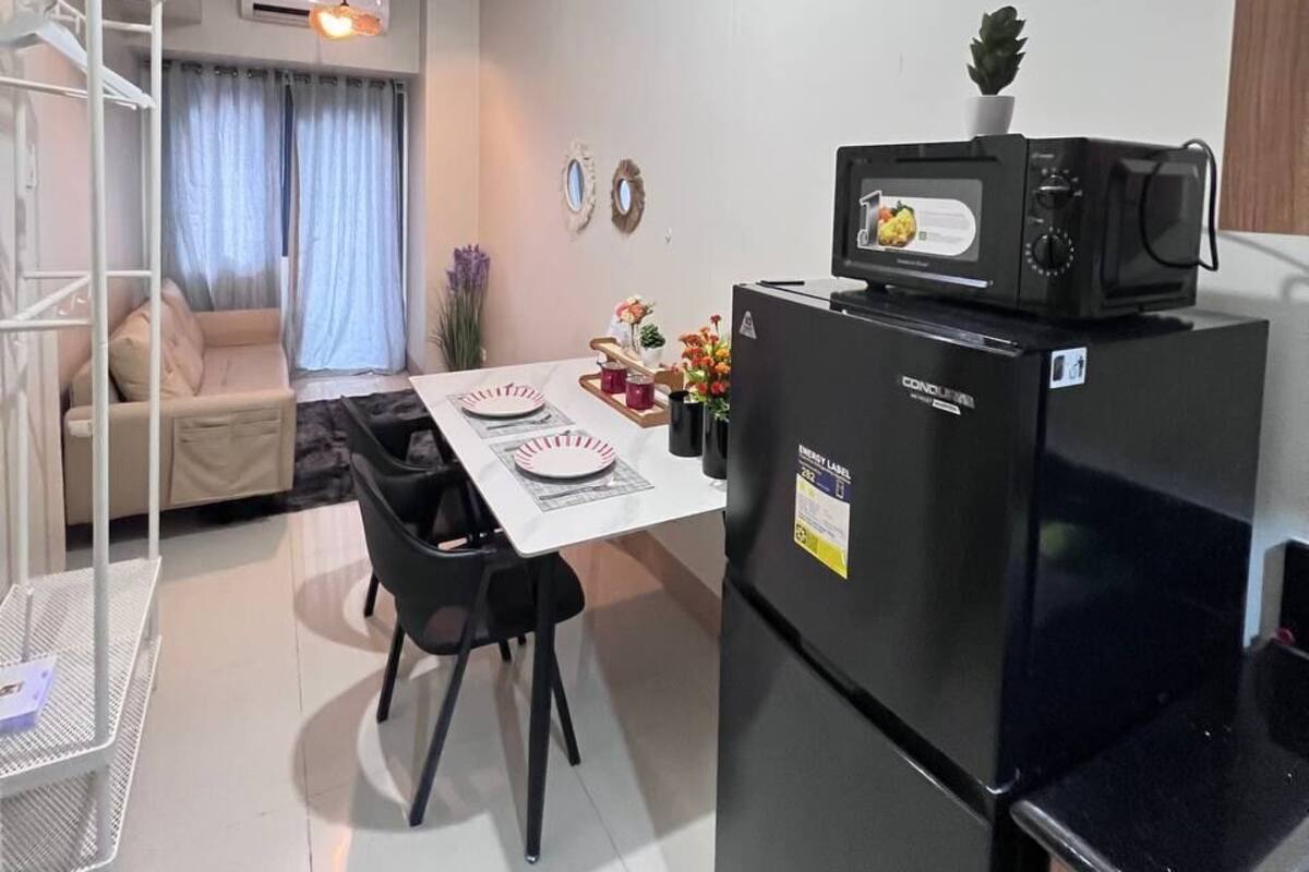 Cocina compacta con refrigerador, microondas y mesa para dos.