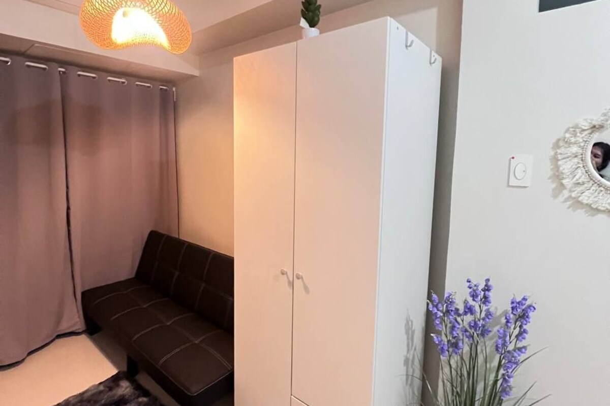 Una camera da letto con un letto, un armadio, tende, un lampadario e una pianta in vaso.