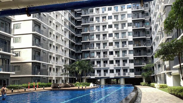 Edifício residencial com várias varandas e uma piscina.