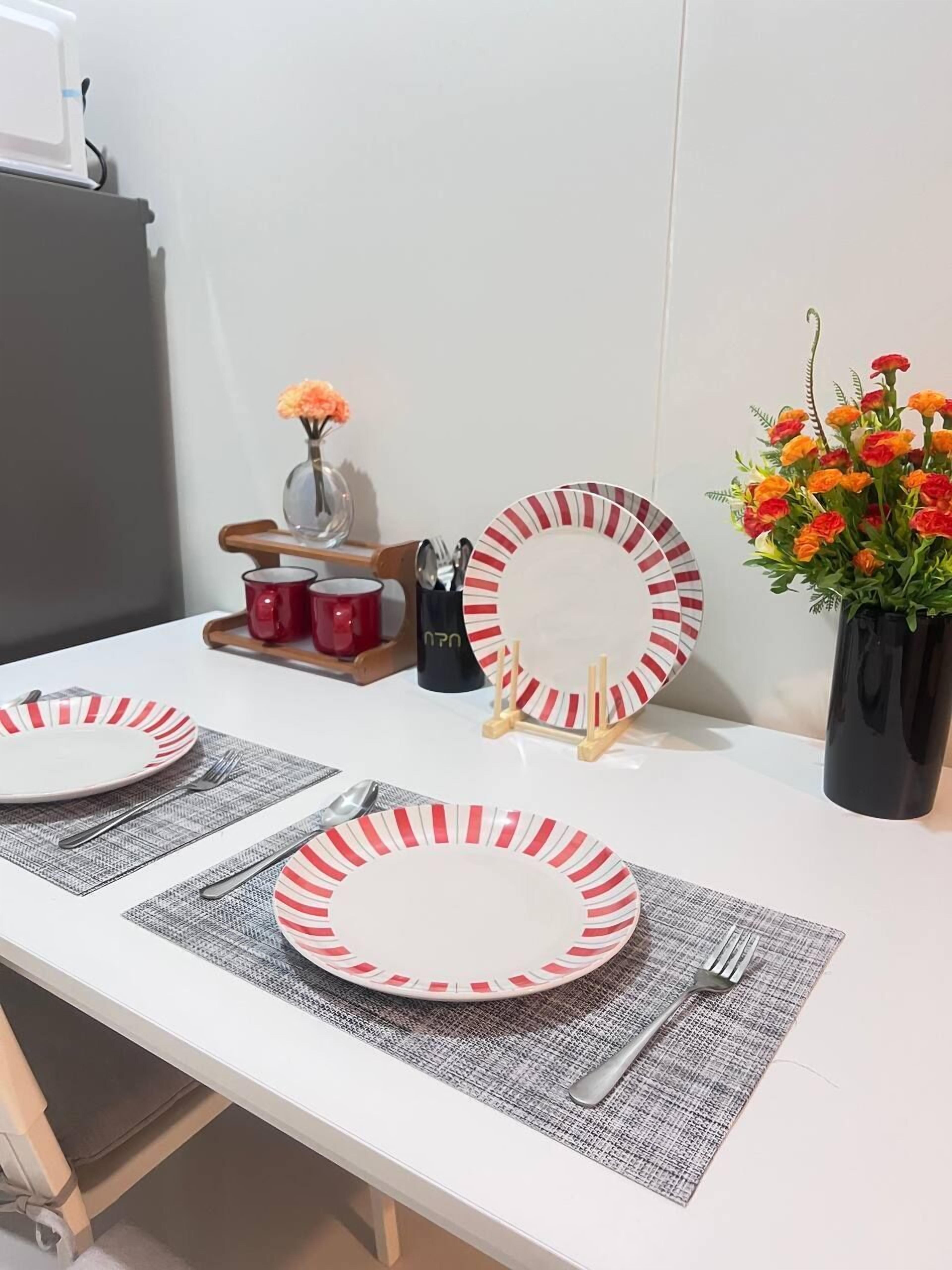 Una mesa de comedor con dos platos, cubiertos y un florero con flores.