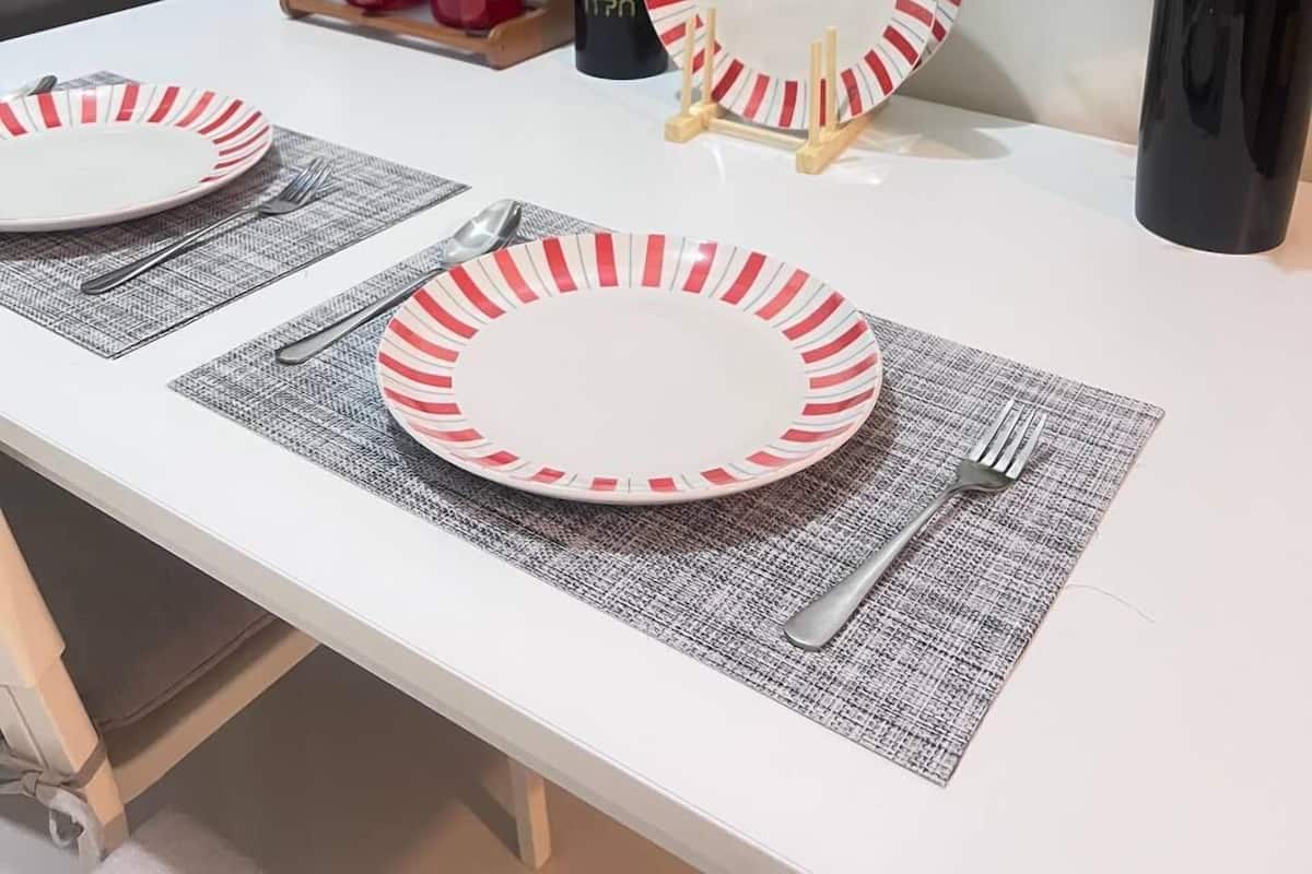 Una mesa de comedor con dos platos, cubiertos y un florero con flores.