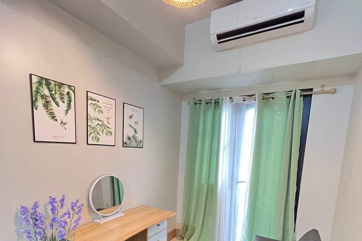 Una sala moderna con un sofá, un escritorio, un espejo y una planta en maceta.
