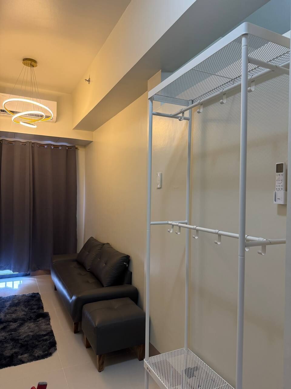 A modern living room with a sofa, ottoman, and a white metal wardrobe.