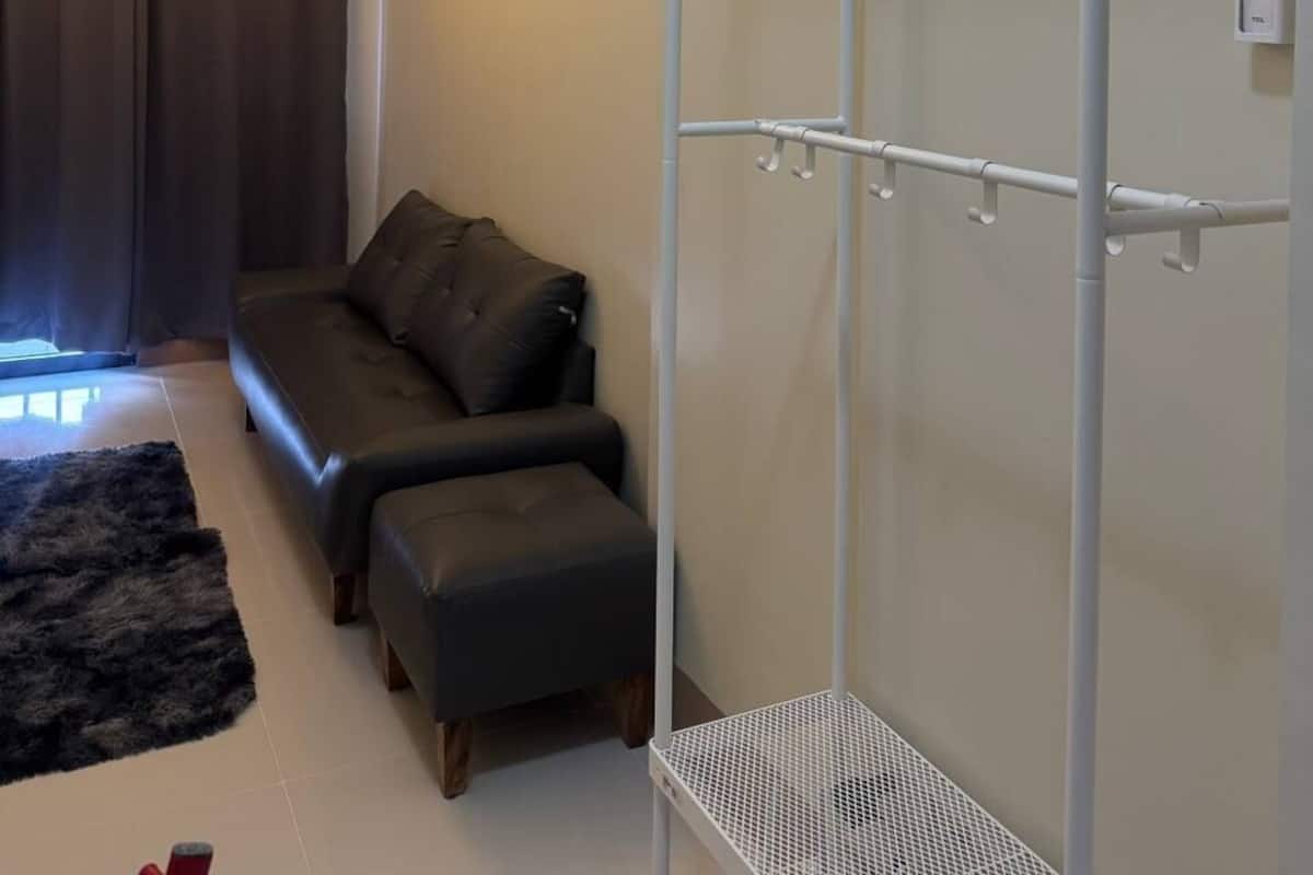 A modern living room with a sofa, ottoman, and a white metal wardrobe.