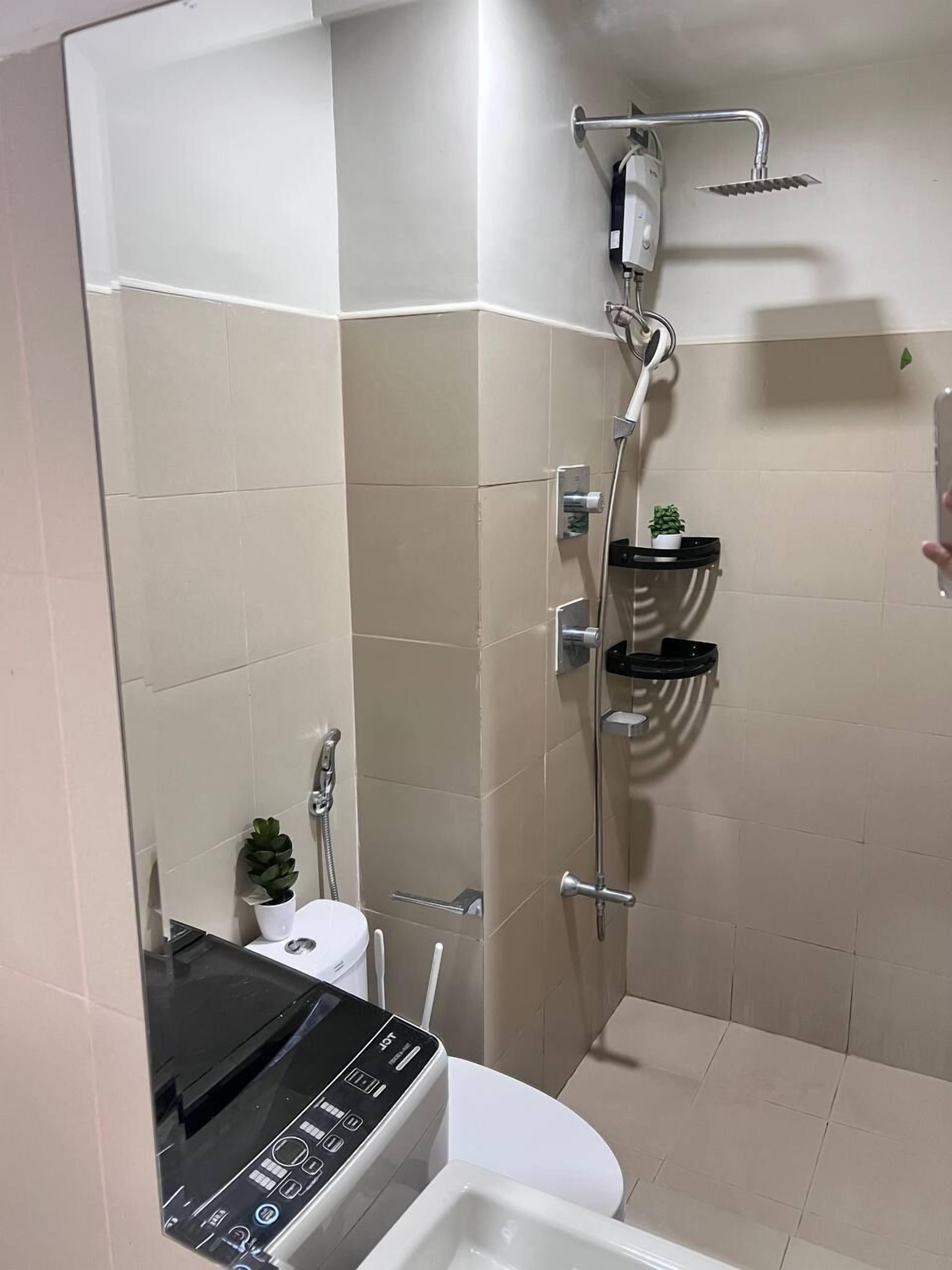 Een moderne badkamer met een douche, toilet en een zwart apparaat, mogelijk een koffiezetapparaat, op het aanrecht.