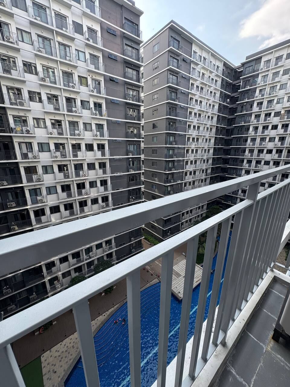 Un edificio residencial de varios pisos con balcones, piscina y cielo despejado.