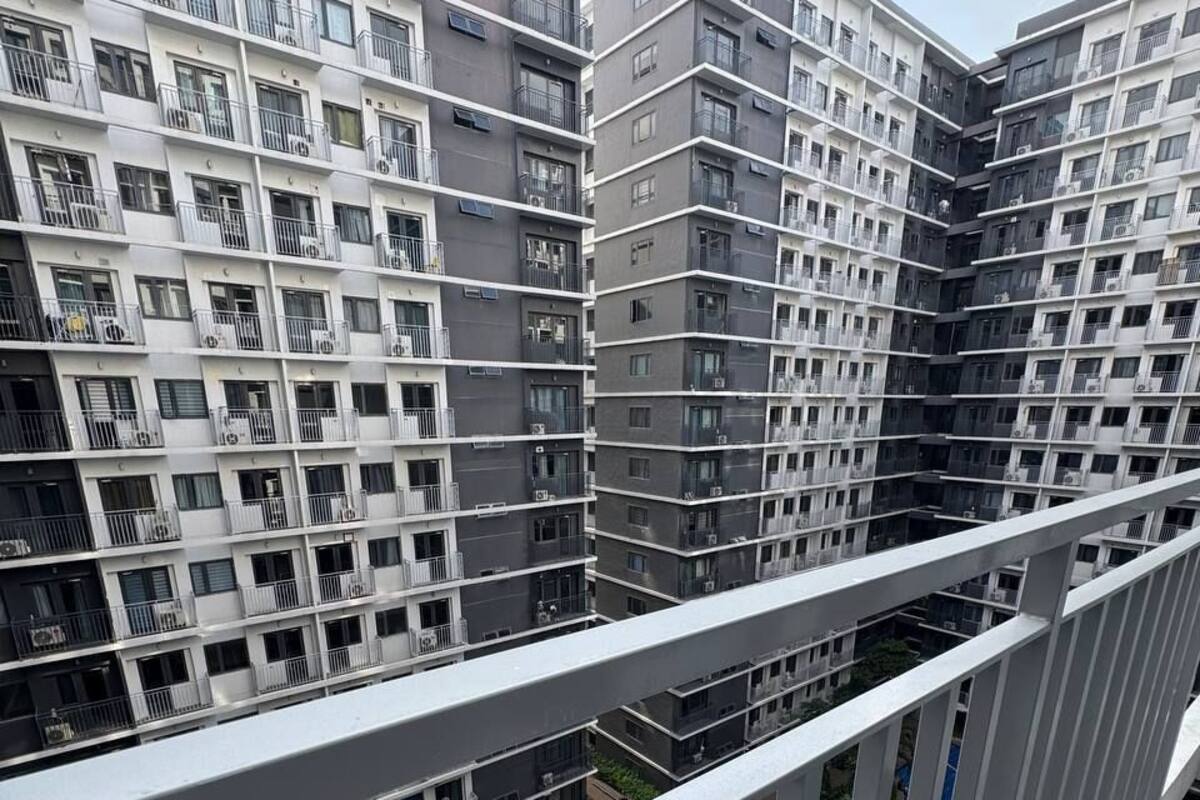 Un edificio residencial de varios pisos con balcones, piscina y cielo despejado.