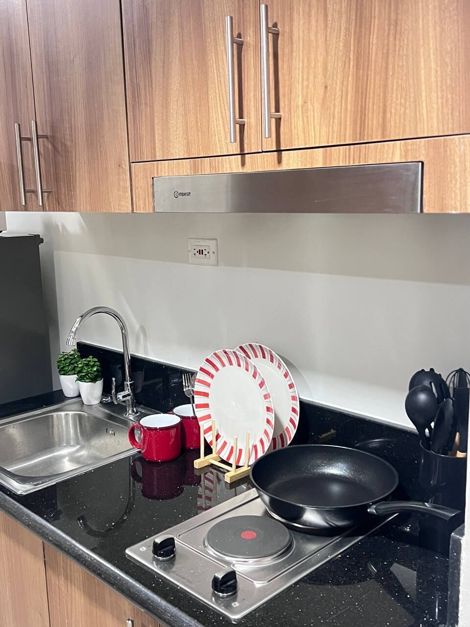 Una cocina con un lavamanos de acero inoxidable, una estufa y armarios de madera.