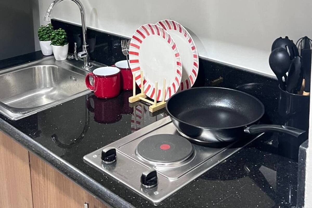 Una cocina con un lavamanos de acero inoxidable, una estufa y armarios de madera.