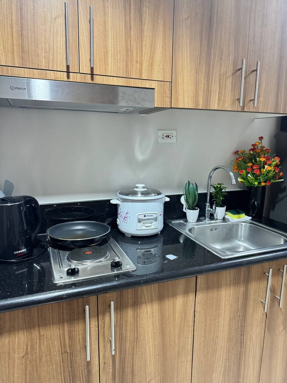 A kitchen with wooden cabinets, a gas stove, a slow cooker, a sink, and a coffee maker.