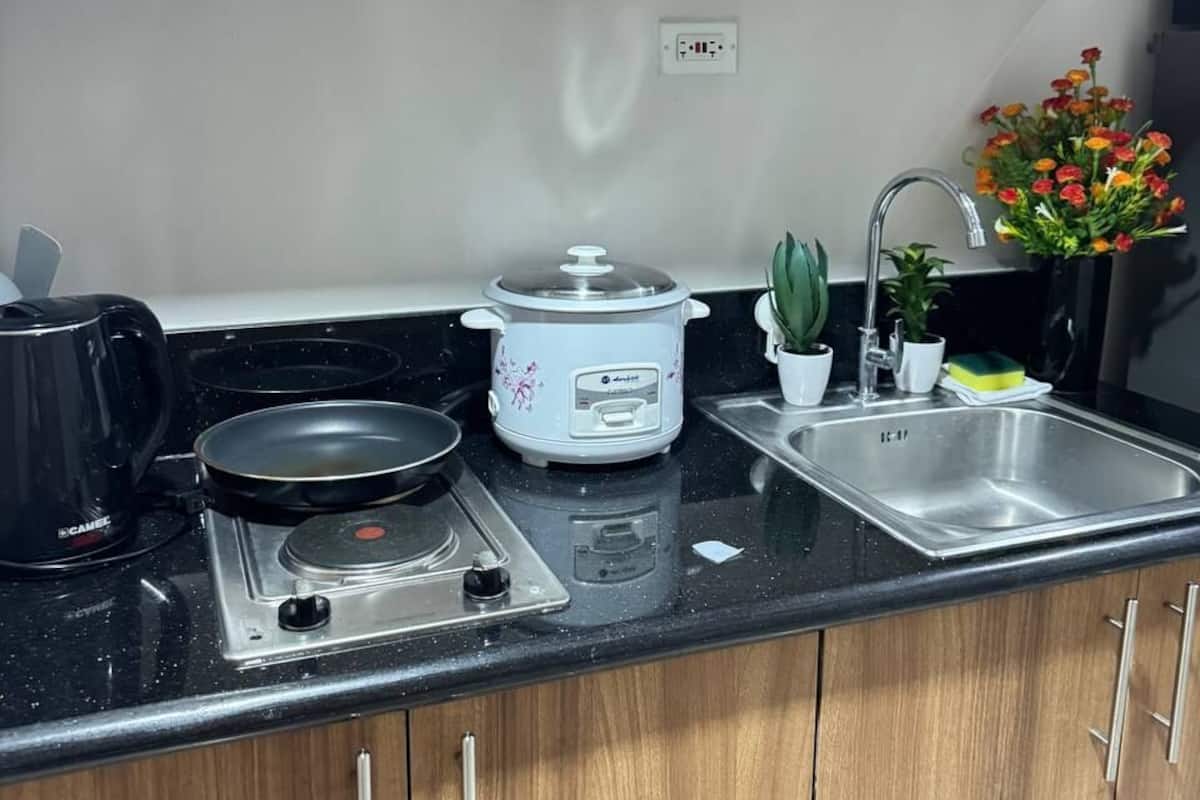 A kitchen with wooden cabinets, a gas stove, a slow cooker, a sink, and a coffee maker.