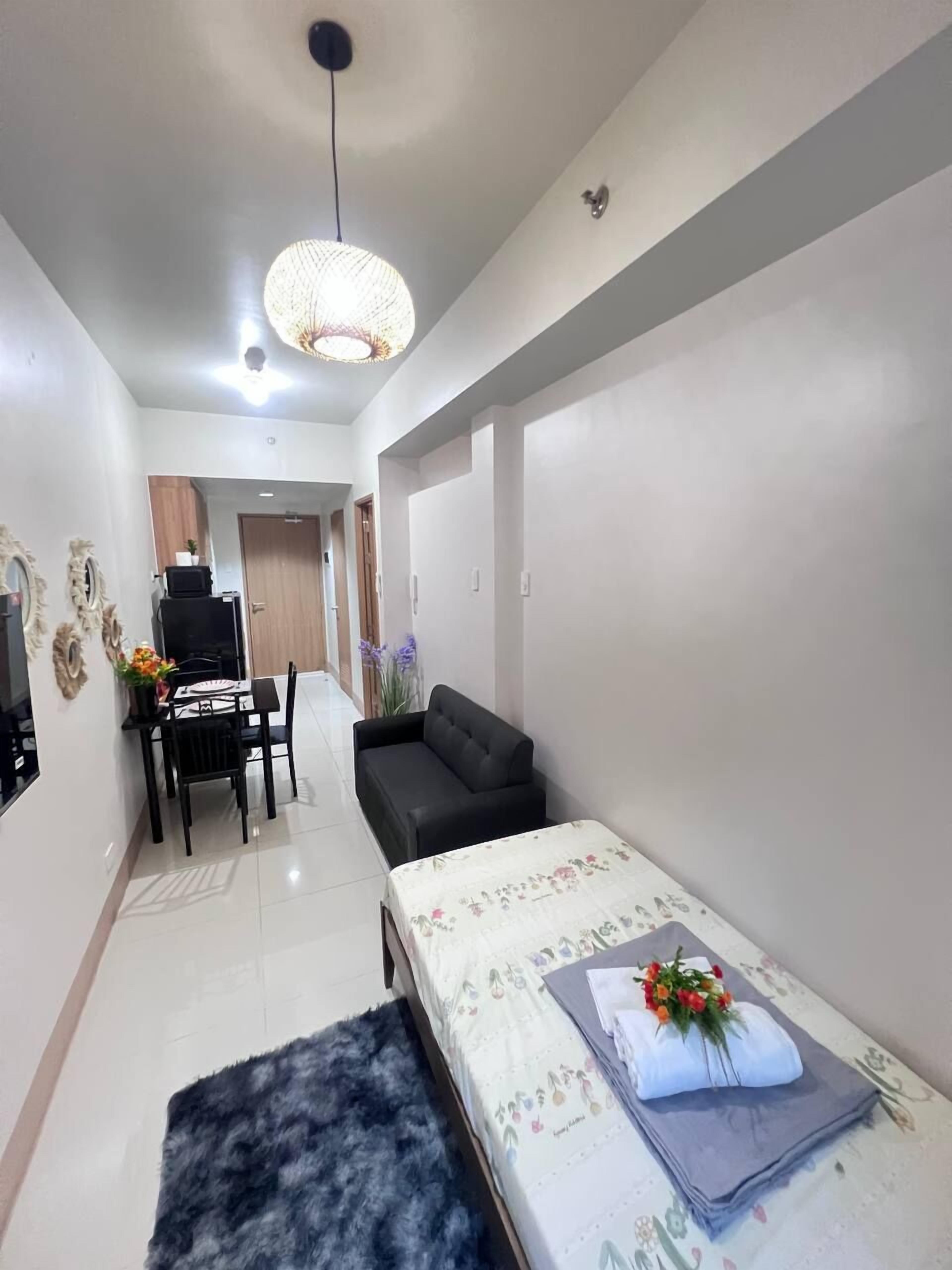A modern living room with a sofa, a dining table with chairs, a small rug, and a decorative wall piece.