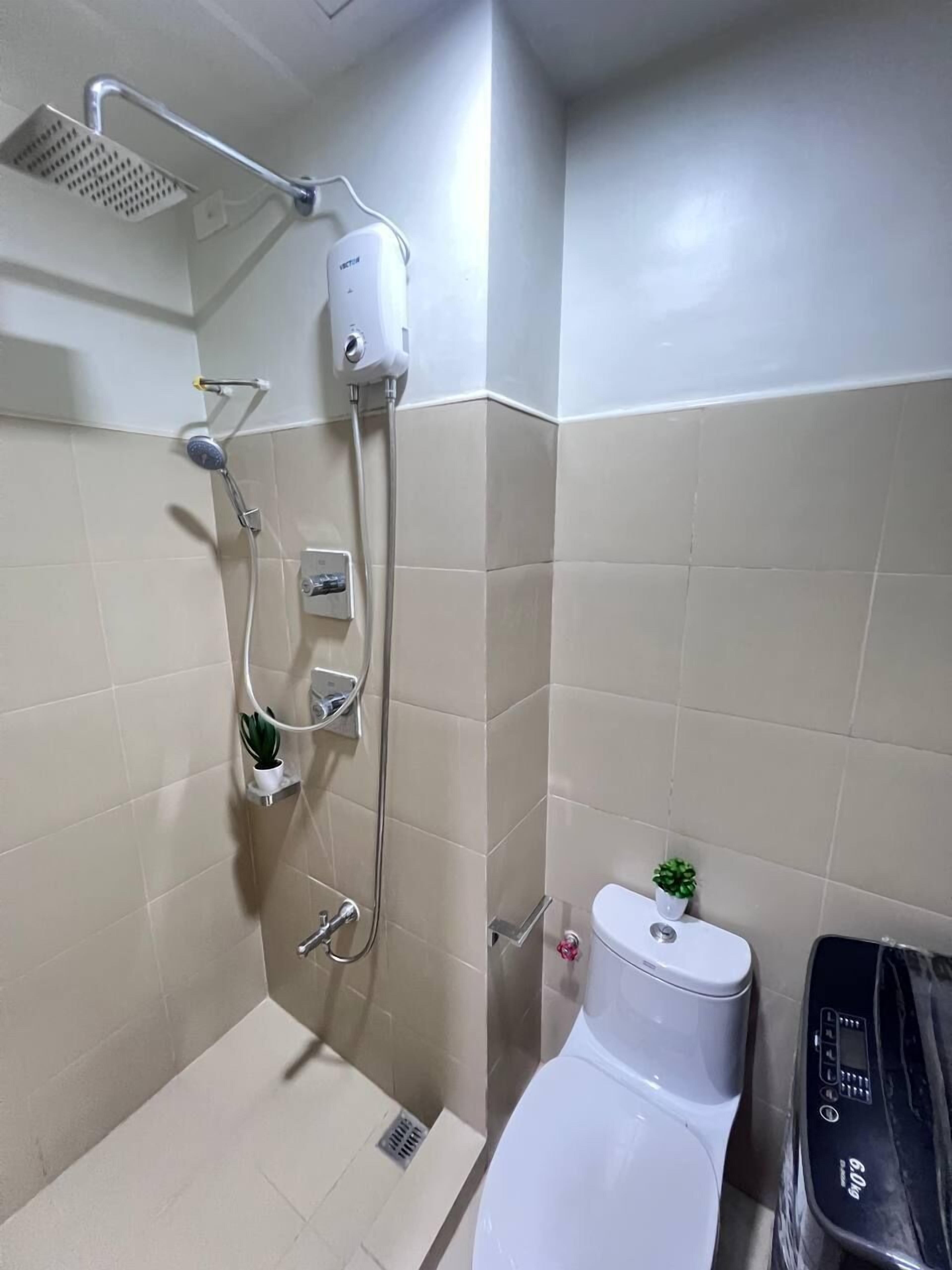 A bathroom with a shower, toilet, and a small potted plant.