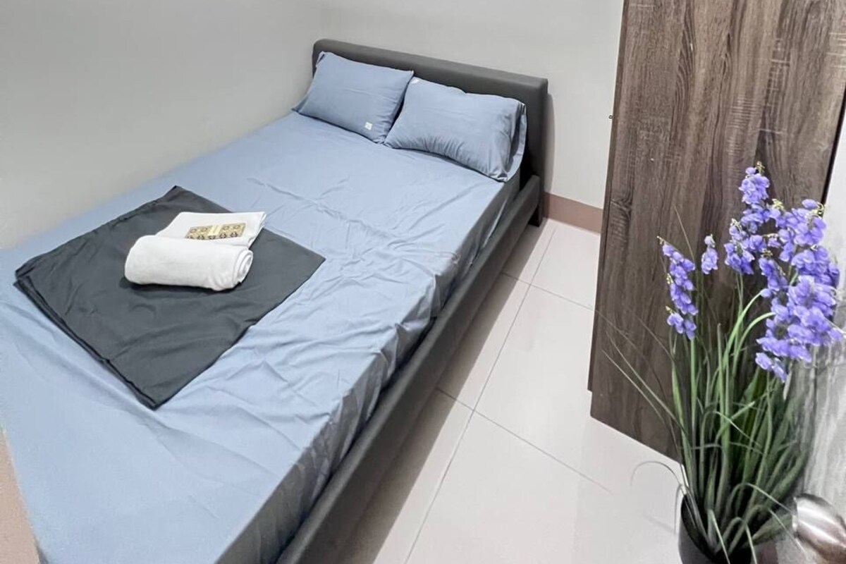 Un dormitorio pequeño y moderno con una cama, un armario de madera y una planta en maceta.