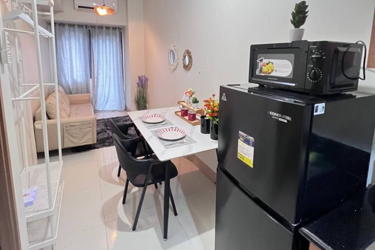 Una cocina compacta con refrigerador, microondas y comedor con mesa y sillas.