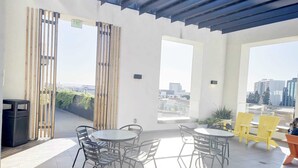 Una terrazza sul tetto con un tavolo rotondo e sedie, un cestino e vista sulla citt à.