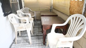 Una habitación con una mesa de madera y cuatro sillas de plástico blancas.