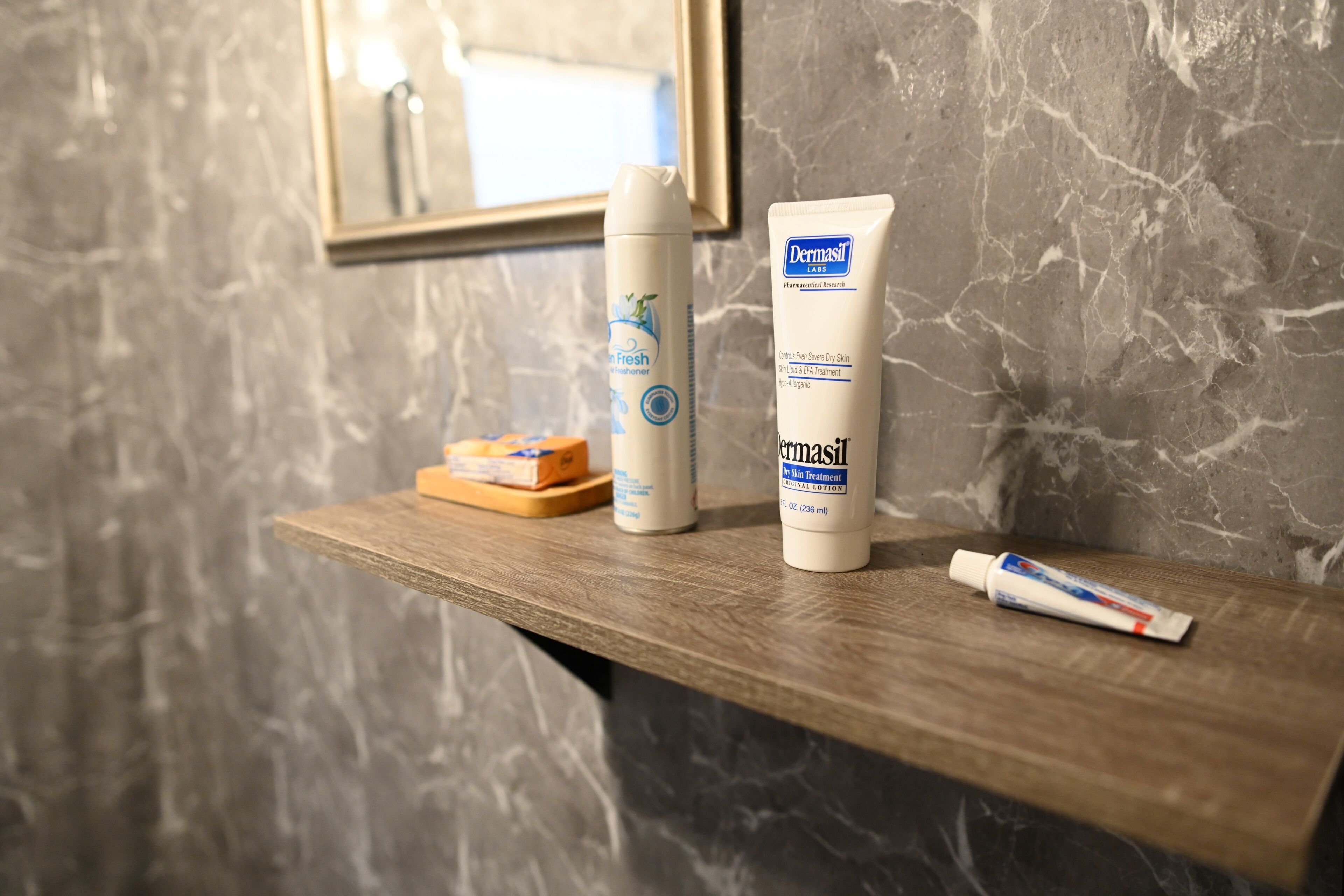 Ein Badezimmerschrank mit einer Dermasil-Flasche, einer Creme-Tube und einer Seife.