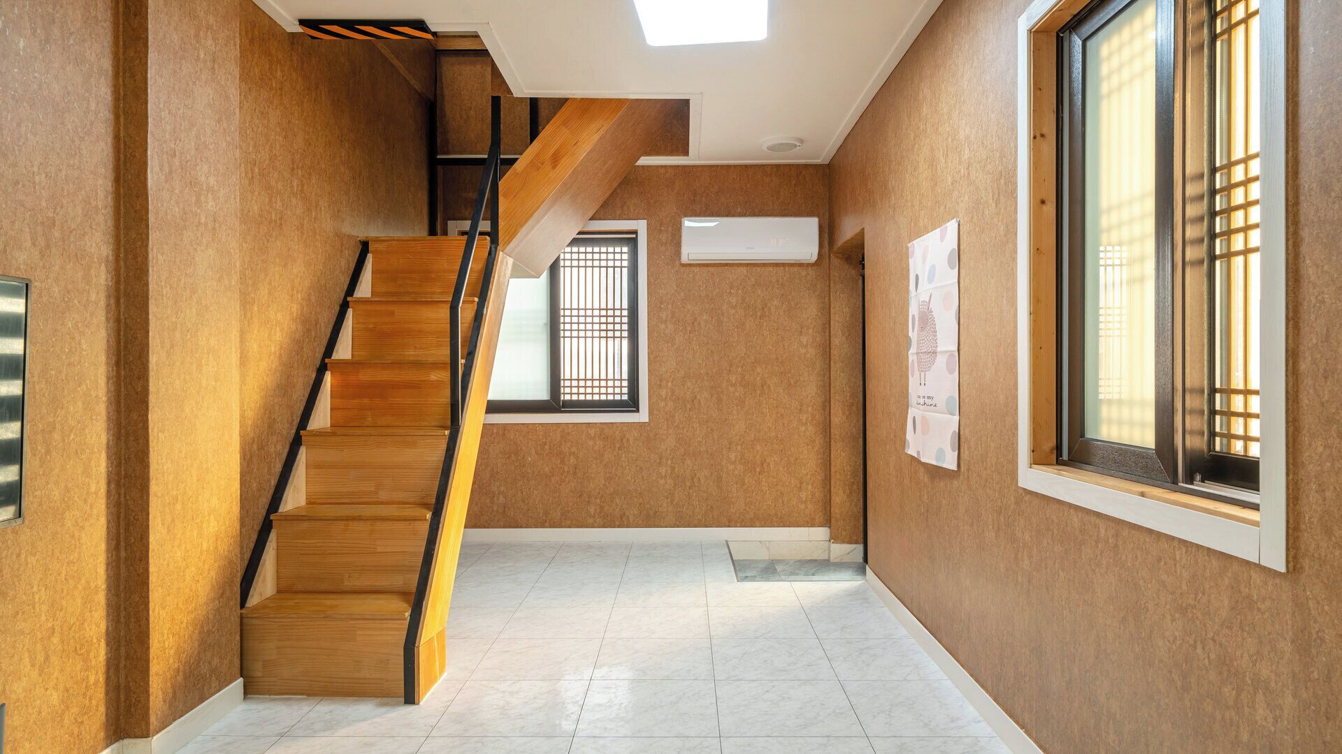 A modern interior with a wooden staircase, large windows, and a tiled floor.
