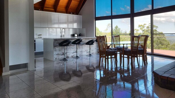 A modern kitchen with white cabinets, a large island, and a dining area with wooden chairs and a glass table.