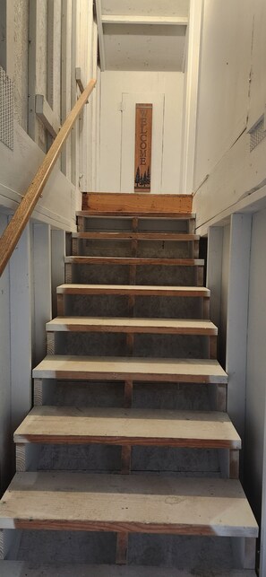 Una escalera de madera con barandilla que conduce a una plataforma con un letrero de madera.