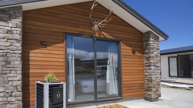 A modern building with a stone facade, large sliding glass doors, and a small outdoor planter. - Hunter studio room-Twin (Lake Tekapo)