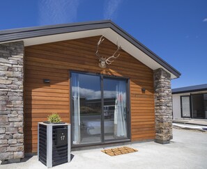A modern building with a stone facade, large sliding glass doors, and a small outdoor planter. - Hunter studio room-Twin (Lake Tekapo)
