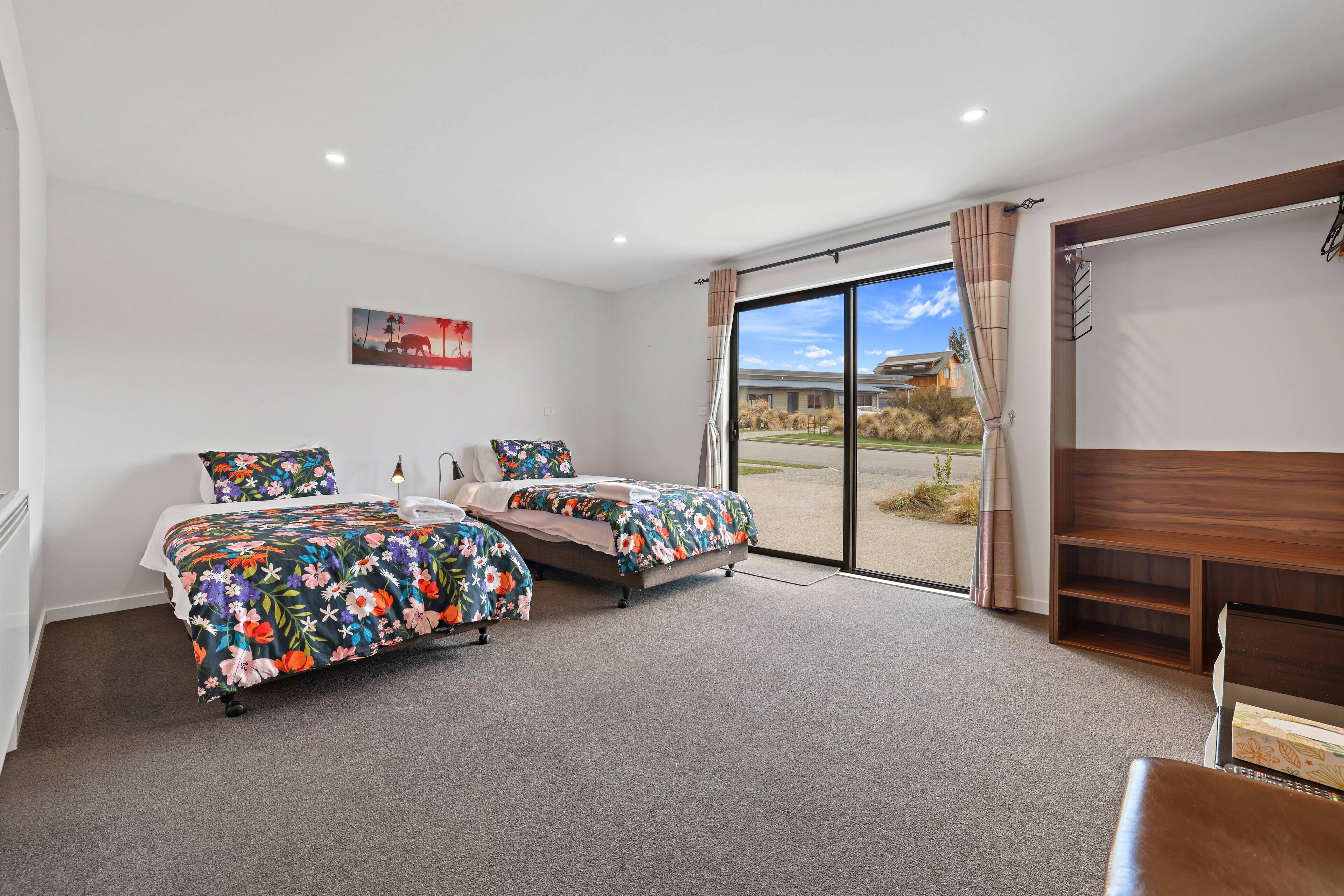 A bedroom with two beds, a large window, and a view of the outdoors.
