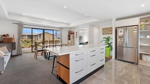 A modern kitchen with a large island, built-in appliances, and a dining area with natural light.