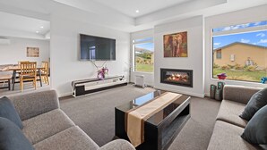 A modern living room with a flat-screen TV, a fireplace, and a large window with a view of the outdoors.
