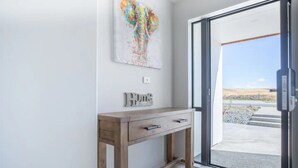 A modern entryway with a wooden console table, a colorful abstract painting, and a 'Home' sign.