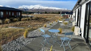 Ein Gebäude mit einer Terrassenanlage, Sitzgelegenheiten im Freien und Blick auf schneebedeckte Berge.