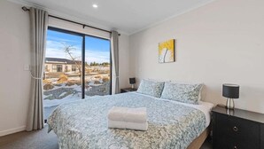 Un dormitorio con una cama grande, una mesita de noche, una lámpara y un cuadro en la pared.
