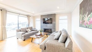 Ein modernes Wohnzimmer mit zwei grauen Sofas, einem Couchtisch und einem an der Wand befestigten Flachbildfernseher.