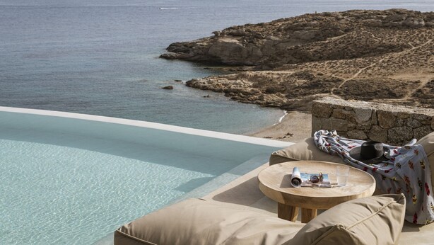 A poolside area with a view of the sea and rocky terrain. - Seafront 9BDR Serenity in Mykonos (Mikonos)