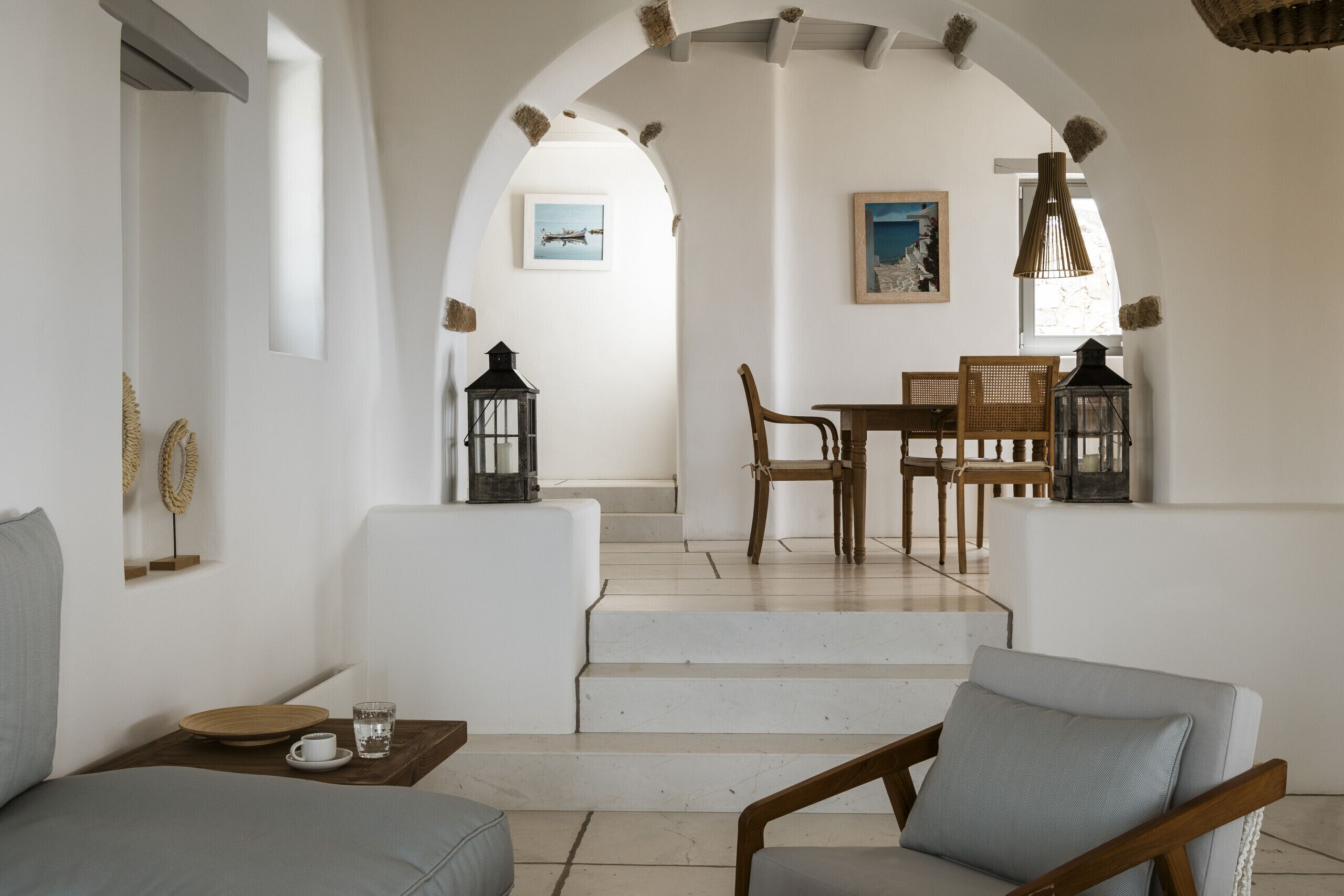 Een modern interieur met een trap naar een eetgedeelte, met een tafel en stoelen, en uitzicht op de omgeving.