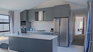 A modern kitchen with grey cabinetry, a central island, and stainless steel appliances. - Starry Heaven 3bdr3ba (Lake Tekapo)