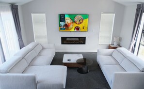 Relax in this stylish living room with a large flat-screen TV, fireplace, and comfortable seating for two.