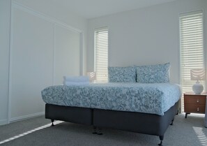 Relax in this serene bedroom with a large bed, nightstand, and lamp.