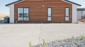 Een modern gebouw met twee verdiepingen, een houten gevel en grote ramen.