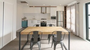 Een moderne keuken met witte kasten, een houten tafel en vier stoelen.