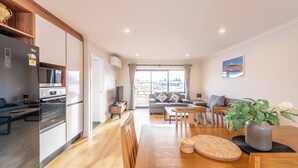 A modern kitchen with a built-in oven and a dining area with wooden furniture. - Mirror Lake 2 Bedroom A (Lake Tekapo)